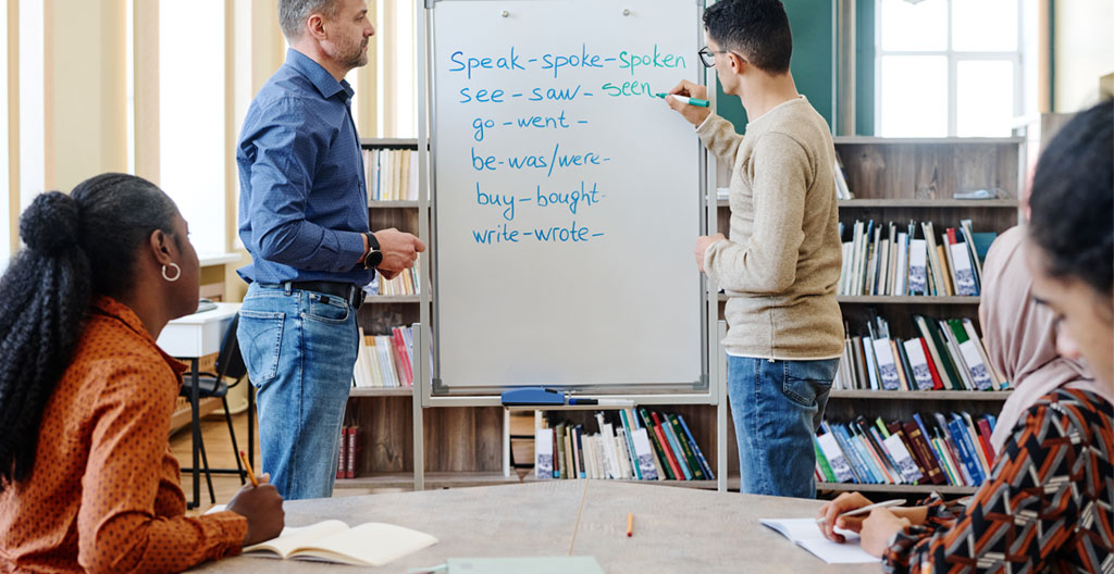Gros plan sur un carnet de notes ouvert affichant du vocabulaire anglais écrit à la main, avec un stylo moderne posé sur une table en bois clair